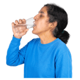 A woman in a blue top drinking a glass of water.