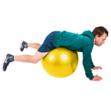A boy in green balancing on a big yellow fitness ball.
